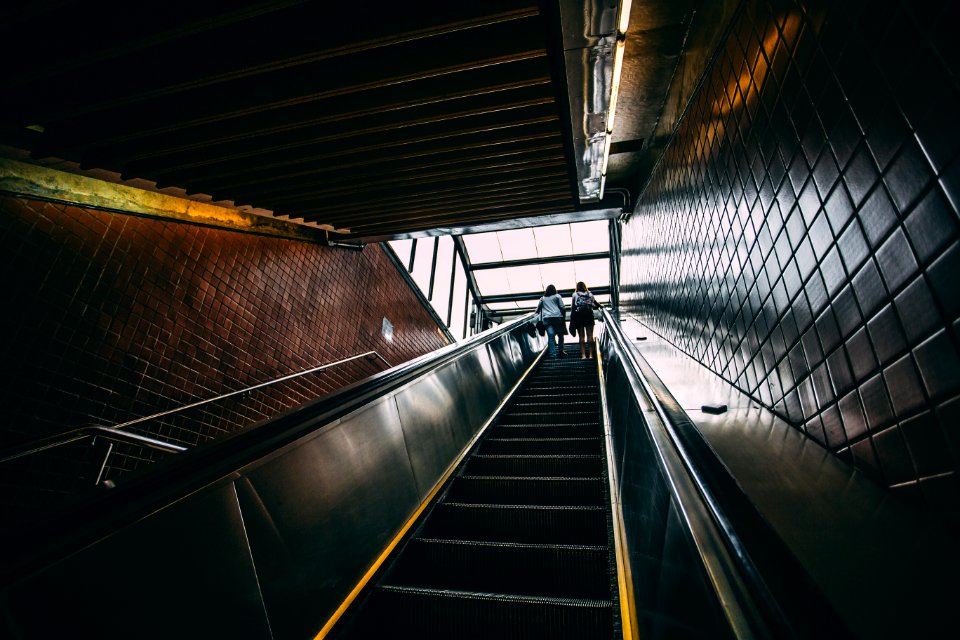 2 Person Standing On Black Escalator During Daytime photo