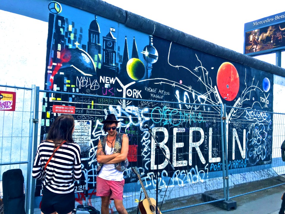 Man Wearing Black Waistcoat And White Tank Tops Standing Near A Mural