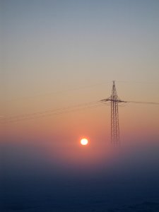 Electricity Pylon In Foggy Sunrise