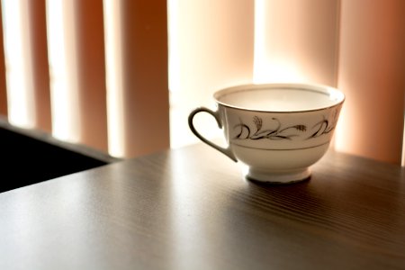 White And Black Ceramic Teacup On Brown Wooden Surface photo