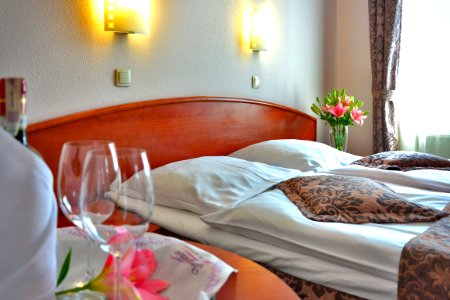 Clear Wine Glass On Brown Wooden Table Top Near Bed photo