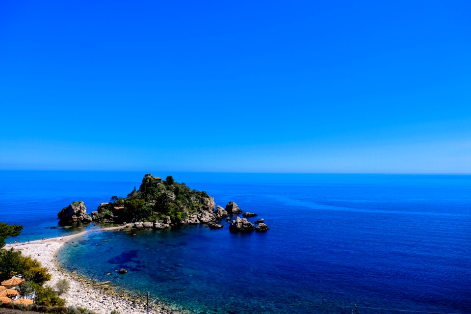 White Beach Shoreline Near Gray Rocks Under Blue Sky During Daytime photo