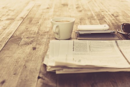 Newspaper And White Ceramic Cup On Brown Wooden Table photo