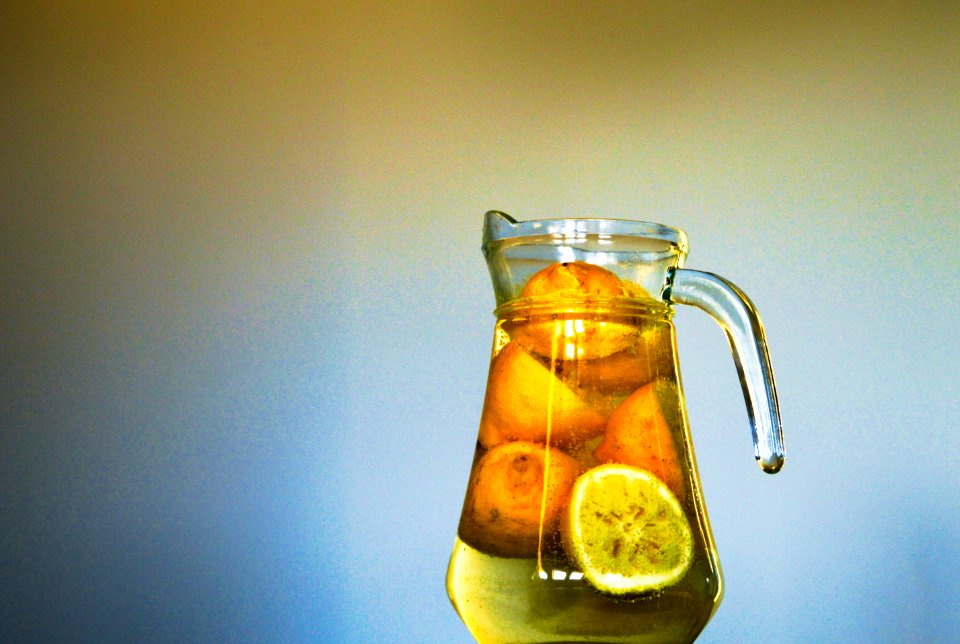 Clear Glass Pitcher With Sliced Yellow Round Fruit Inside photo