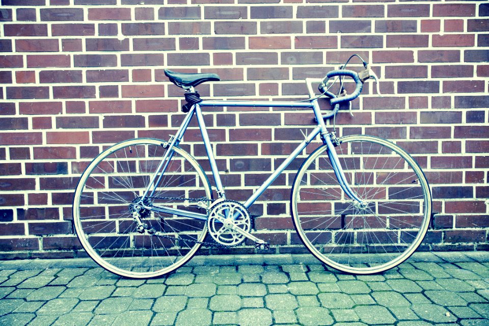 Teal And Black Road Bike Near Black And Brown Brick Wall photo