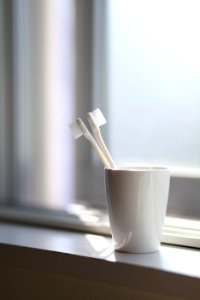 Two White Toothbrush Inside The White Ceramic Cup photo