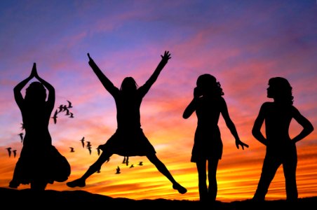 Silhouette Of 4 Women With The Background Of Birds Flying Under Yellow And Grey Sky