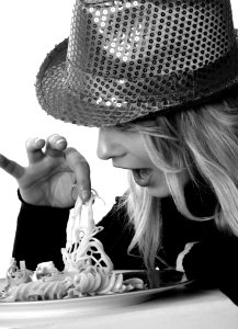 Woman In Sweater And Sequin Fedora Hat Holding Noodles In Grayscale Photography photo