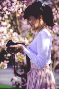 Woman In White Long Sleeve Top And Pink Skirt Holding Black Dslr Camera