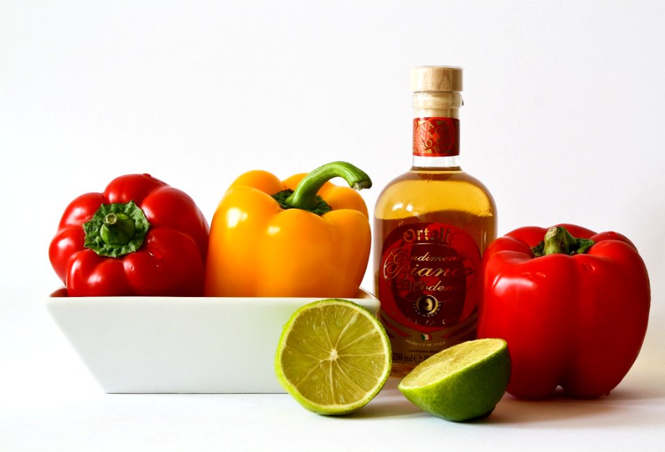 Red And Green Bell Pepper Inside White Ceramic Tray Near To Bottle And Lemon