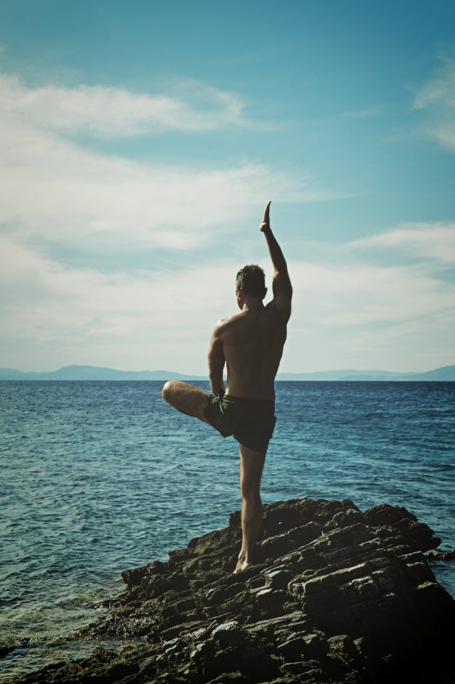 Topless Man Standing On Rock Formation Using Right Leg Only