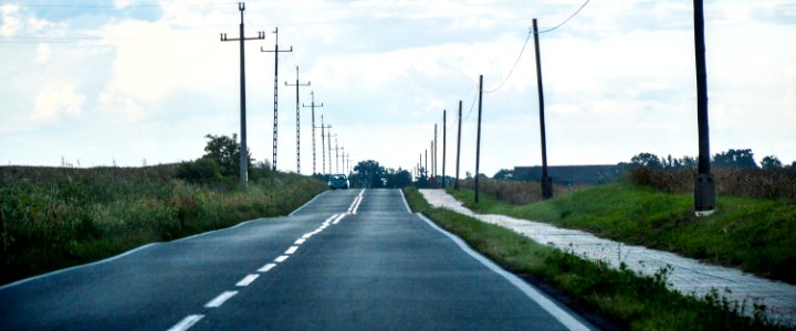 Gray Asphalt Road Between Green Grass And Gray Electric Post During Daytime