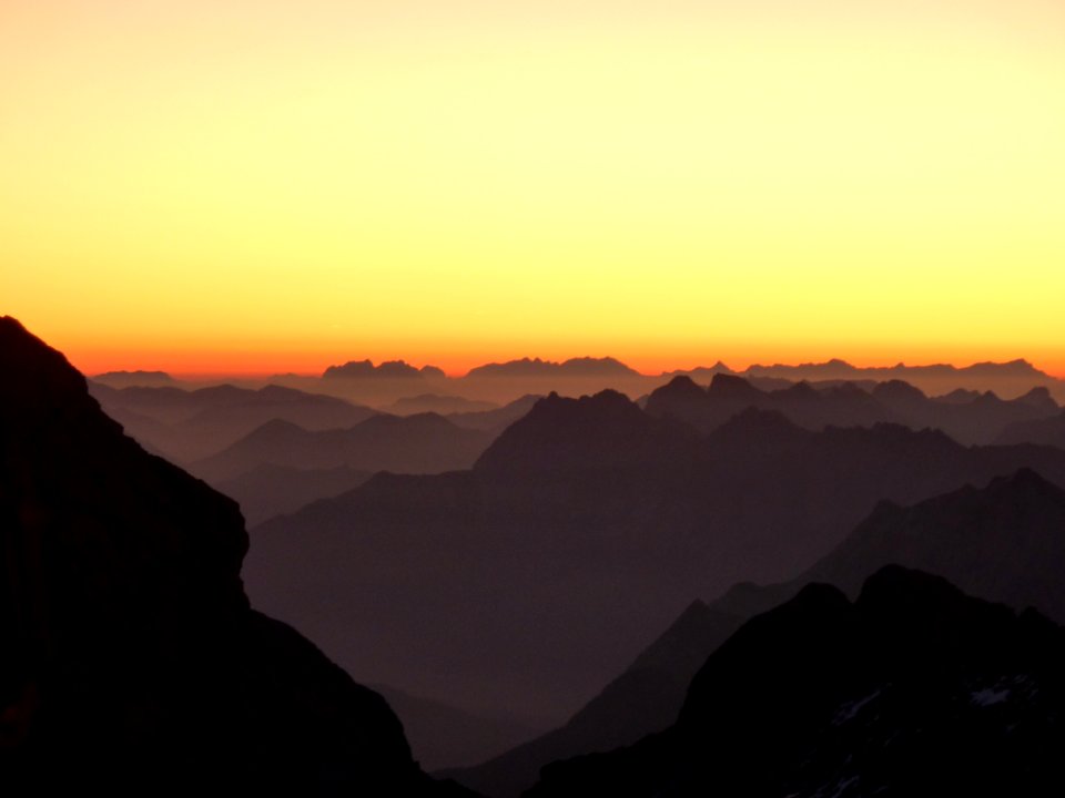 Silhouette Of Hills Under Orange And Yellow Sky During Sunset