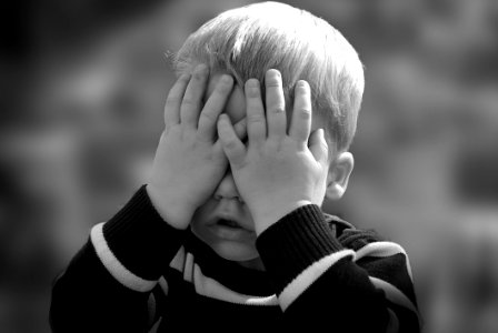 Boy In Black And White Sweater Covering His Face With His Tow Hand photo