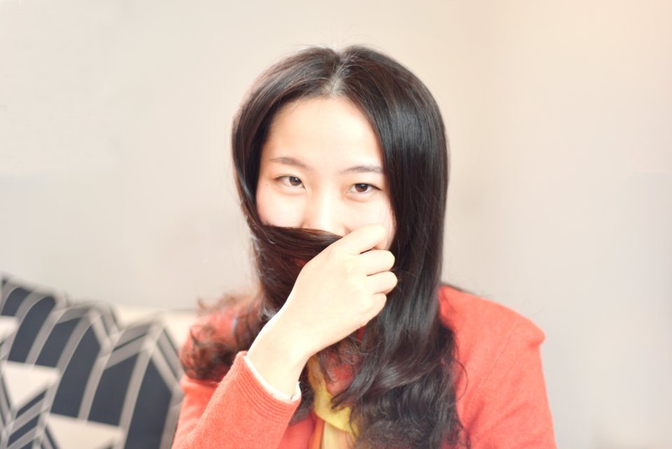 Woman Wearing Orange Blazer Sitting Beside Beige Wall