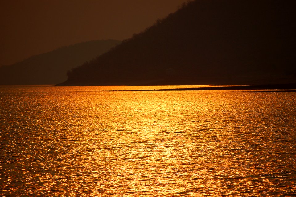 Blue Sea Near Brown Mountain During Sunset