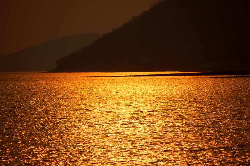 Blue Sea Near Brown Mountain During Sunset photo