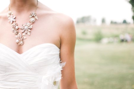 Woman In White Dress Wearing Gold Chunky Necklace During Daytime photo