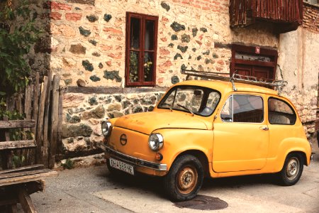 Yellow Nissan Classic Car Beside Gray Beige Concrete Building photo