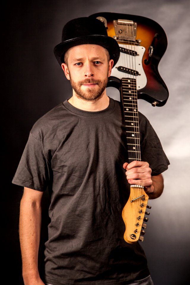 Man In Black T Shirt Holding Electric Guitar Upside Down