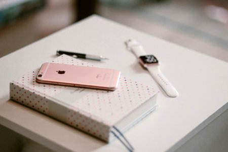 Rose Gold Iphone 6 S On Top Of White Covered Book photo