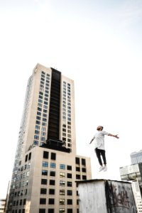 Man Wearing White Long Sleeve Shirt Beside White And Black High Rise Building photo