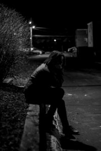 Woman Wearing Jacket Sitting On Concrete During Night Time photo