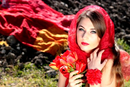 Woman Wearing A Red Scarf Holding Red Flowers photo