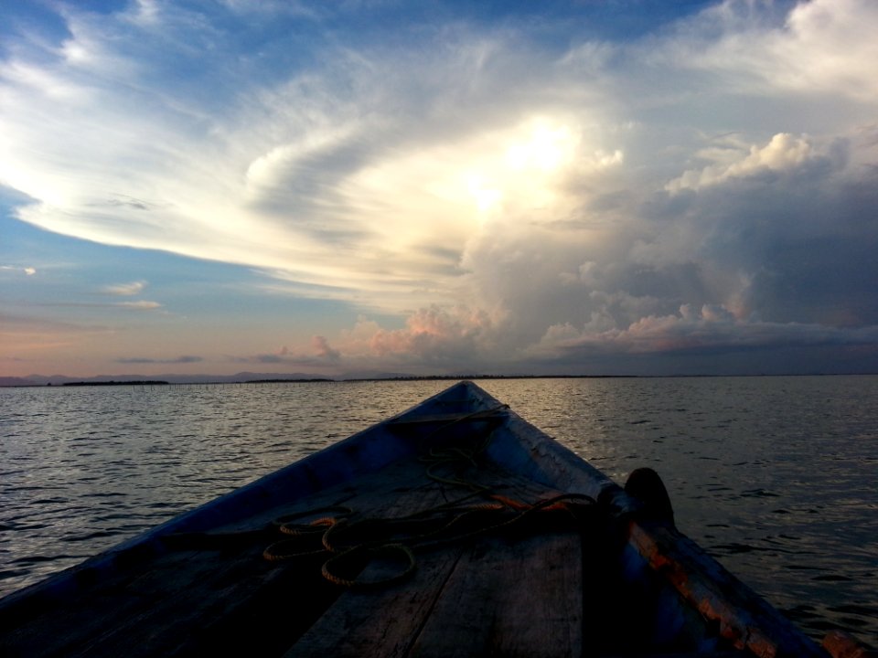 Blue Rowboat On Water Under White Clouds During Daytime