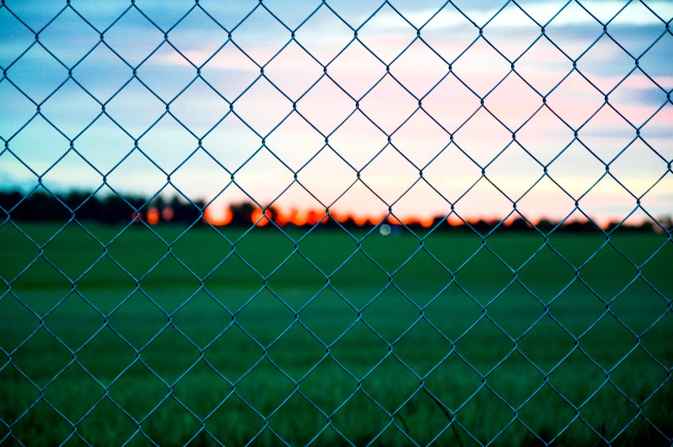 Sunset Over Field Through Fence