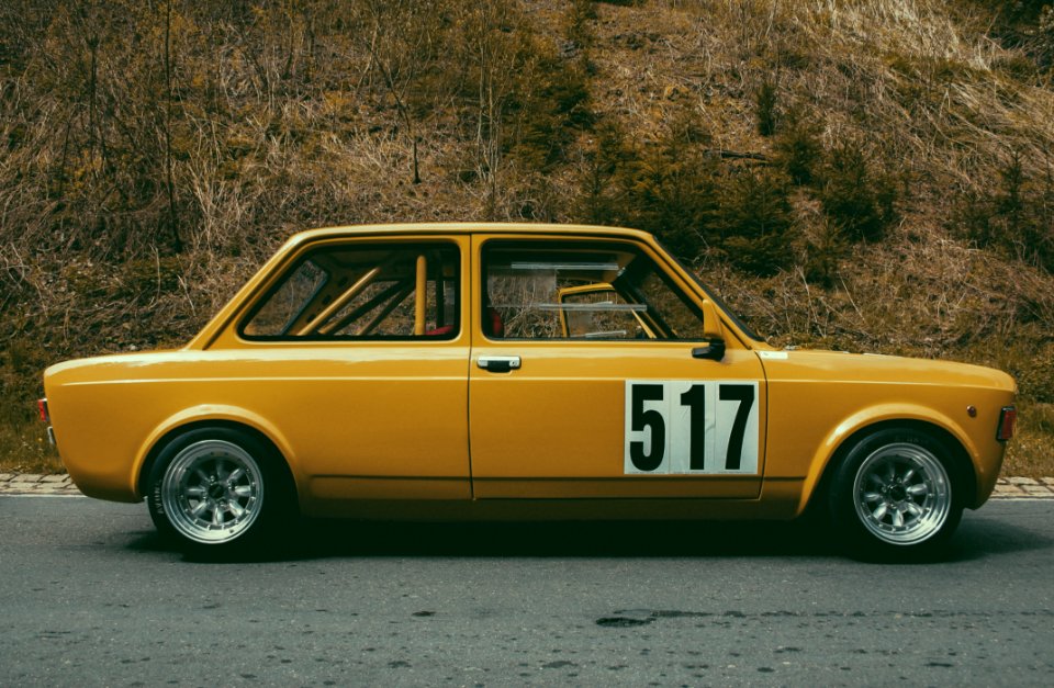 Yellow Sedan Beside Brown Leaf Plant During Daytime