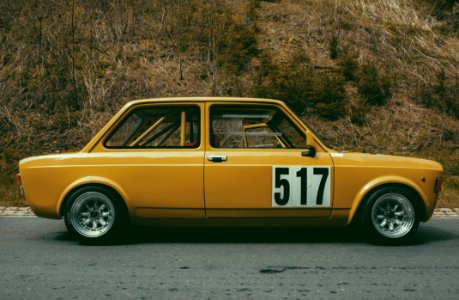 Yellow Sedan Beside Brown Leaf Plant During Daytime