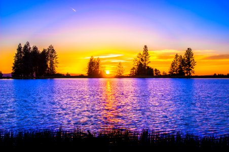 Blue And Orange Sunset Over Lake With Tree Silhouettes photo