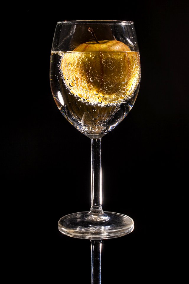 Clear Wine Glass Filled With Clear Beverage With Yellow Round Fruit