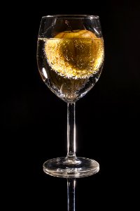 Clear Wine Glass Filled With Clear Beverage With Yellow Round Fruit photo