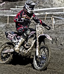 Person Riding On Motorcycle On Motocross Race Track Wearing White And Black Oakley Full Face Helmet During Daytime photo