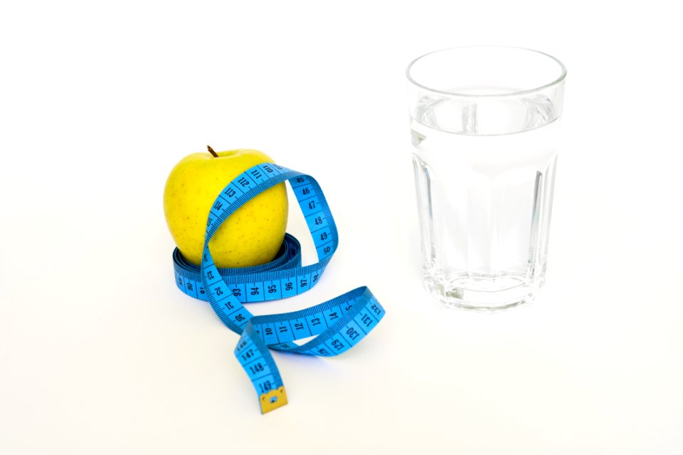 Clear Drinking Glass Near In Blue Tape Measure And Apple Fruit