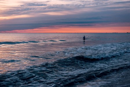 Person Standing In The Sea During Sunset photo