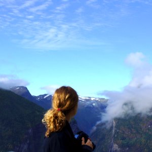 Woman Wearing Black Long Sleeve Shirt Watching On Green And Brown Mountain Under White And Blue Sky During Daytime photo