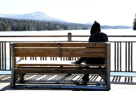 Person On Gray Jacket On Brown Wooden Bench Daytime Photo photo