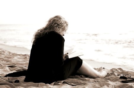 Person Sitting On The Seashore While Reading A Book photo