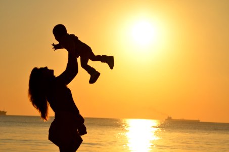 Woman Carrying Baby At Beach During Sunset photo