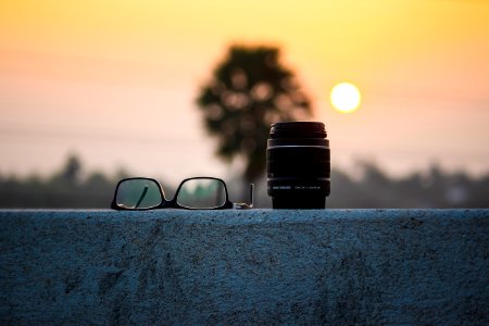 Camera Lens And Eyeglasses At Sunset photo