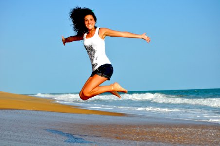 Woman In White Tanktop Jump Over Beach Sand