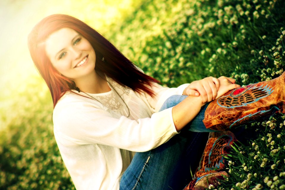 Woman In White Long Sleeve Shirt Sitting On Grass Field During Daytime