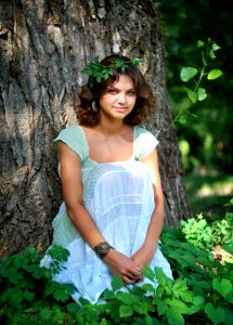 Smiling Woman Wearing Green Leaf Crown With Green And White Sleeveless Dress Sitting In Green Leaf During Day Time