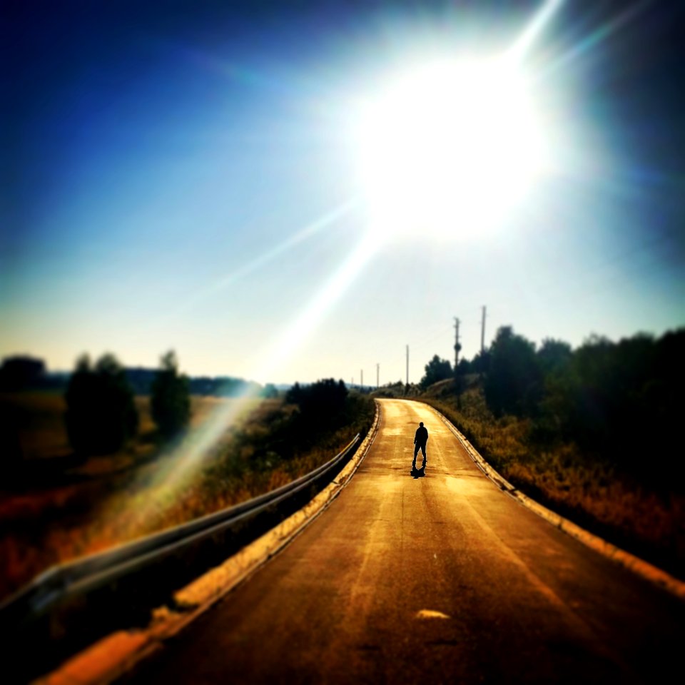 Person Standing On Blacktop Road Under Blue Sky During Daytime photo