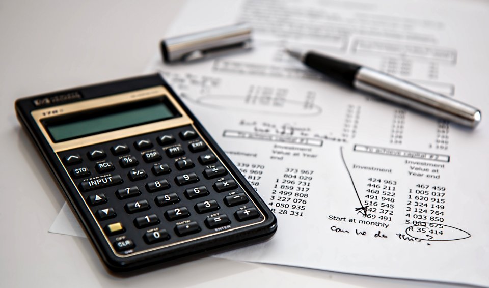 Black Calculator Near Ballpoint Pen On White Printed Paper photo