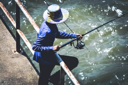 Person In Blue Long Sleeve Shirt And Black Pants Using Fishing Rod photo
