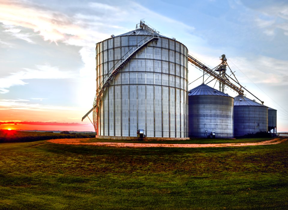 The set sets behind large, metal silos on a farm in Jackson County, Iowa. Original image from Carol M. Highsmith’s America, Library of Congress collection.
